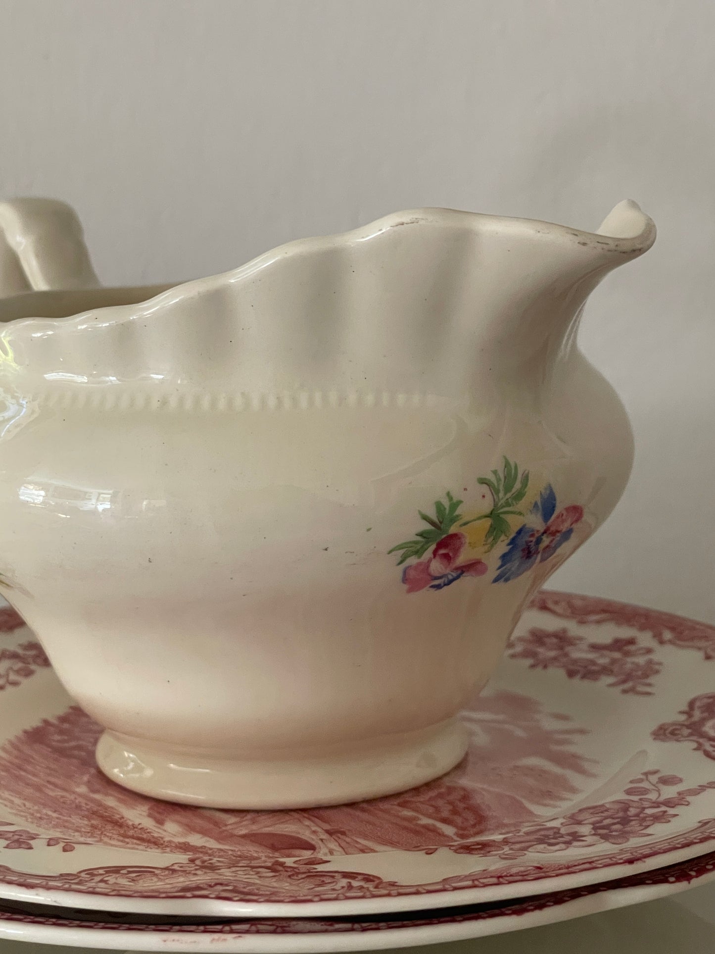 Vintage floral creamware creamer by J. & G. Meakin shown on a lace-covered table with soft candlelight. Multiple angles highlight floral pattern, fluted rim, and noted wear.