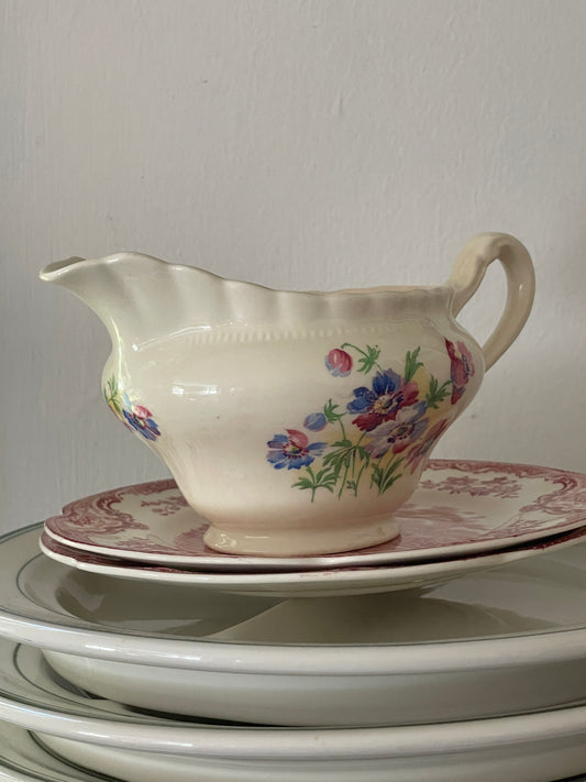 Vintage floral creamware creamer by J. & G. Meakin shown on a lace-covered table with soft candlelight. Multiple angles highlight floral pattern, fluted rim, and noted wear.