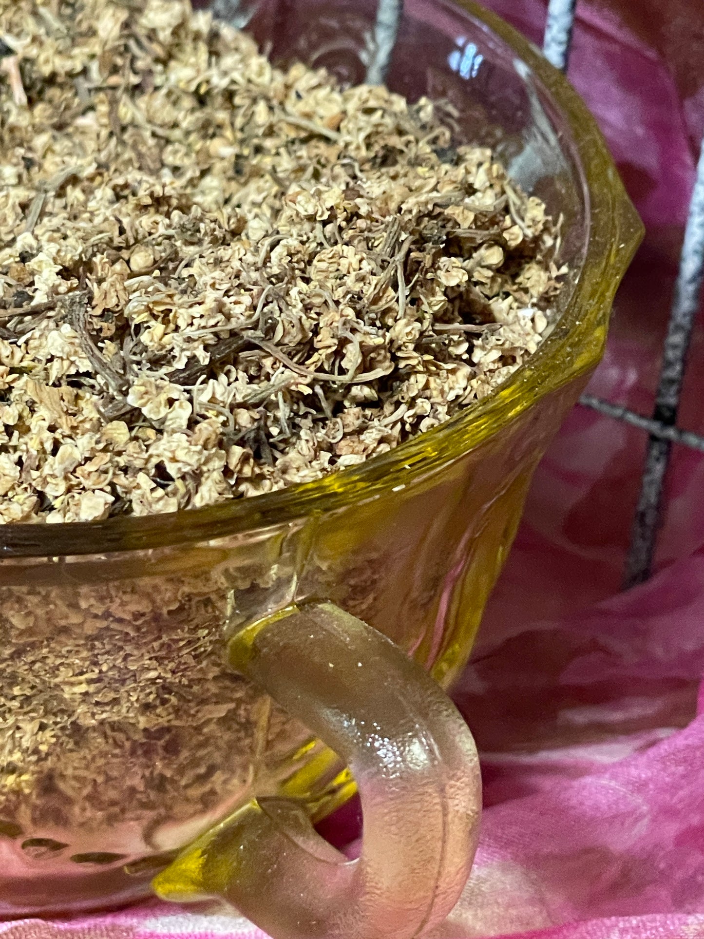 Loose dried elderflowers in a vintage depression glass sugar bowl , soft golden petals glowing in natural sunlight — organic European elder harvested for tea.