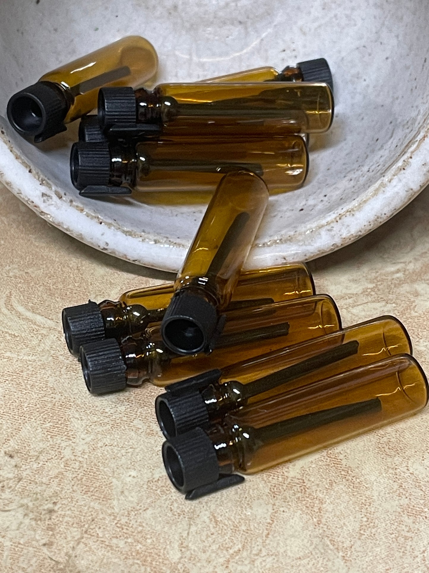 a small pile of amber colored sample vial perfume bottles. heritage floral infusion sample vials.