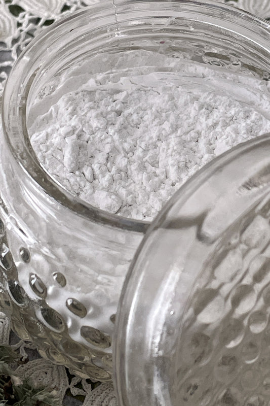 Open powder dish overflowing with natural organic body powder, showcasing a gentle, chemical-free formula made from pure, plant-based ingredients. Ideal for soothing and refreshing skin, offering a natural alternative to traditional body powders.