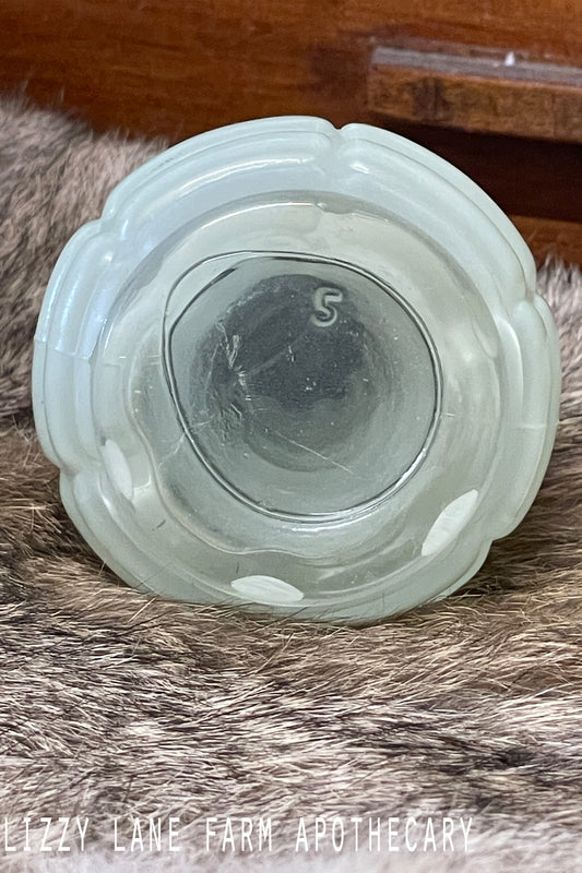 Vintage Anchor Hocking fired-on jadeite green salt shaker with ribbed pattern and bakelite lid photographed on a lace-covered table under candlelight. Multiple angles show the soft color and vintage condition.