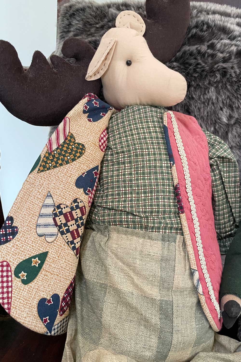 Vintage Stuffed animal wearing a quilted coat with a moose head, rocking in a chair.