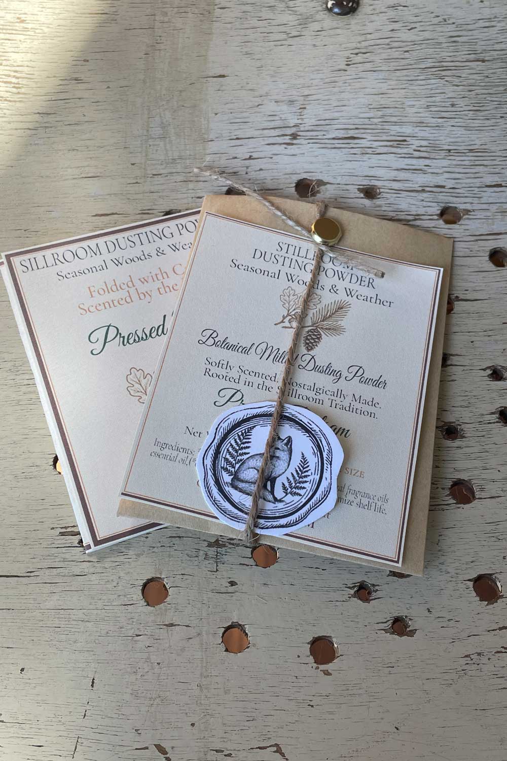 sample size envelope of pressed balsam dusting powder. part of the seasonal woods & weather collection. resting with the limited edition archival cards called fragment cards