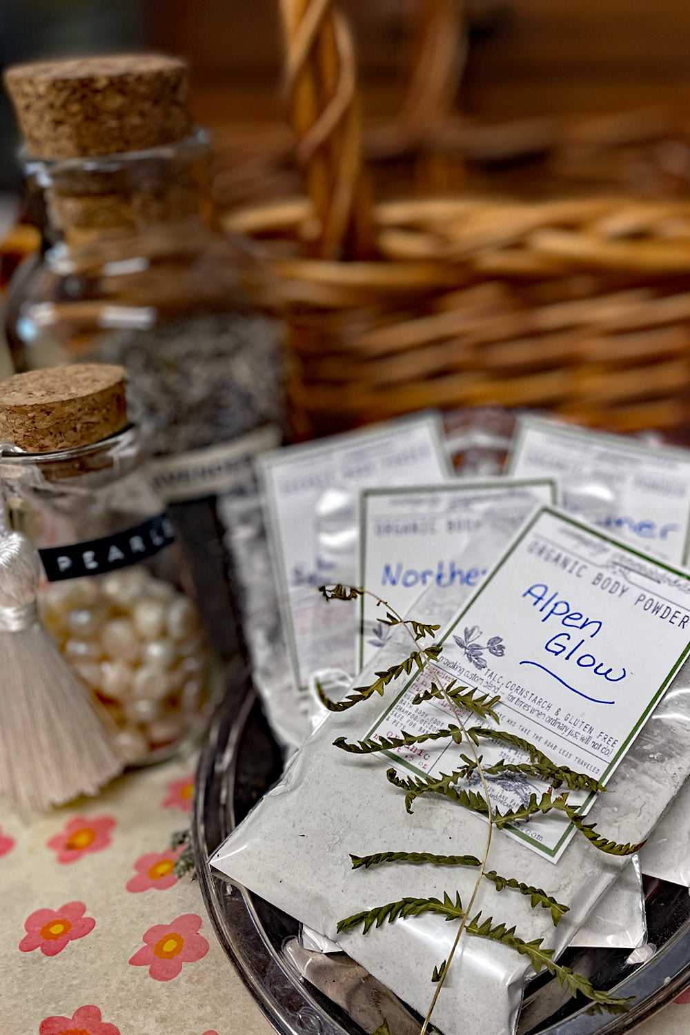 Organic sample-sized body powder in eco-friendly bags, displayed on a rustic table with a wicker basket in the background. Perfect for a gentle, natural alternative to traditional body powders, offering a soothing, chemical-free option for soft, refreshed skin.