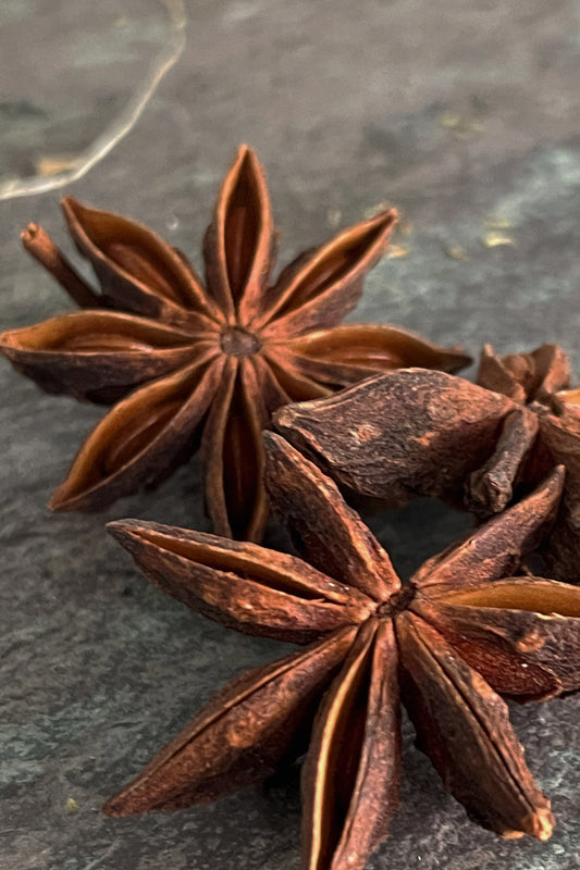 Whole dried star anise pods on slate, organic culinary and herbal spice for tea, simmer pots, and kitchen use.