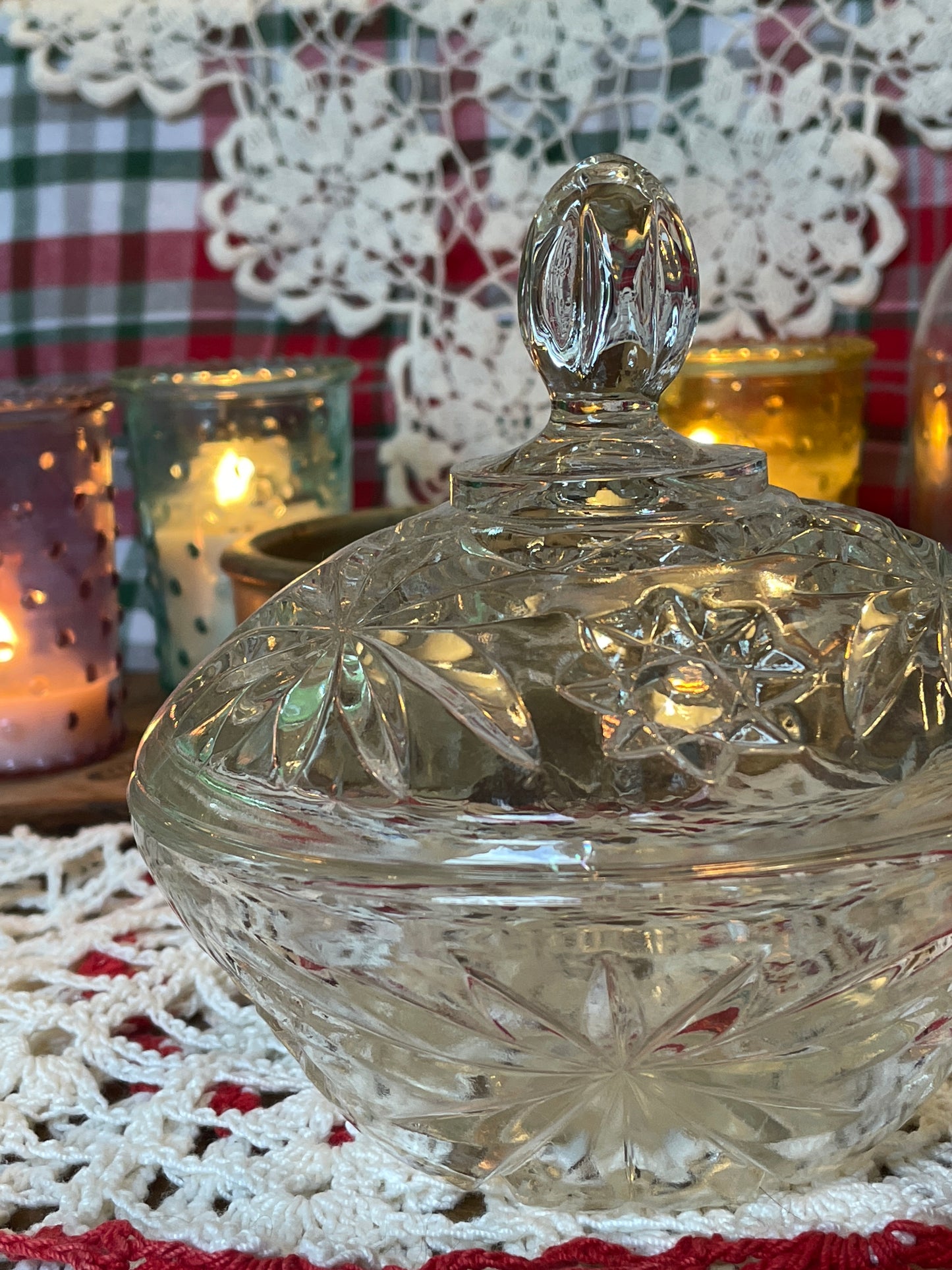 Vintage Anchor Hocking Star of David pressed glass powder dish on red and white crochet doily with warm candlelight in the background.