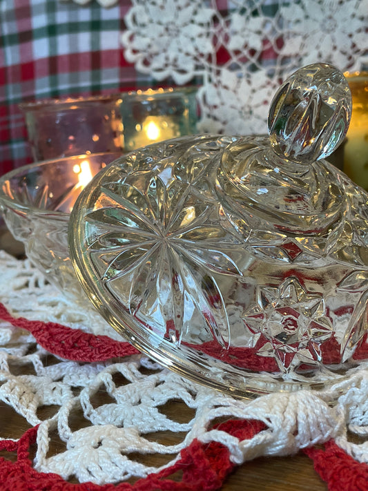 Top angle of glass dish showing finial detail and full pattern, surrounded by vintage charm and candle glow.