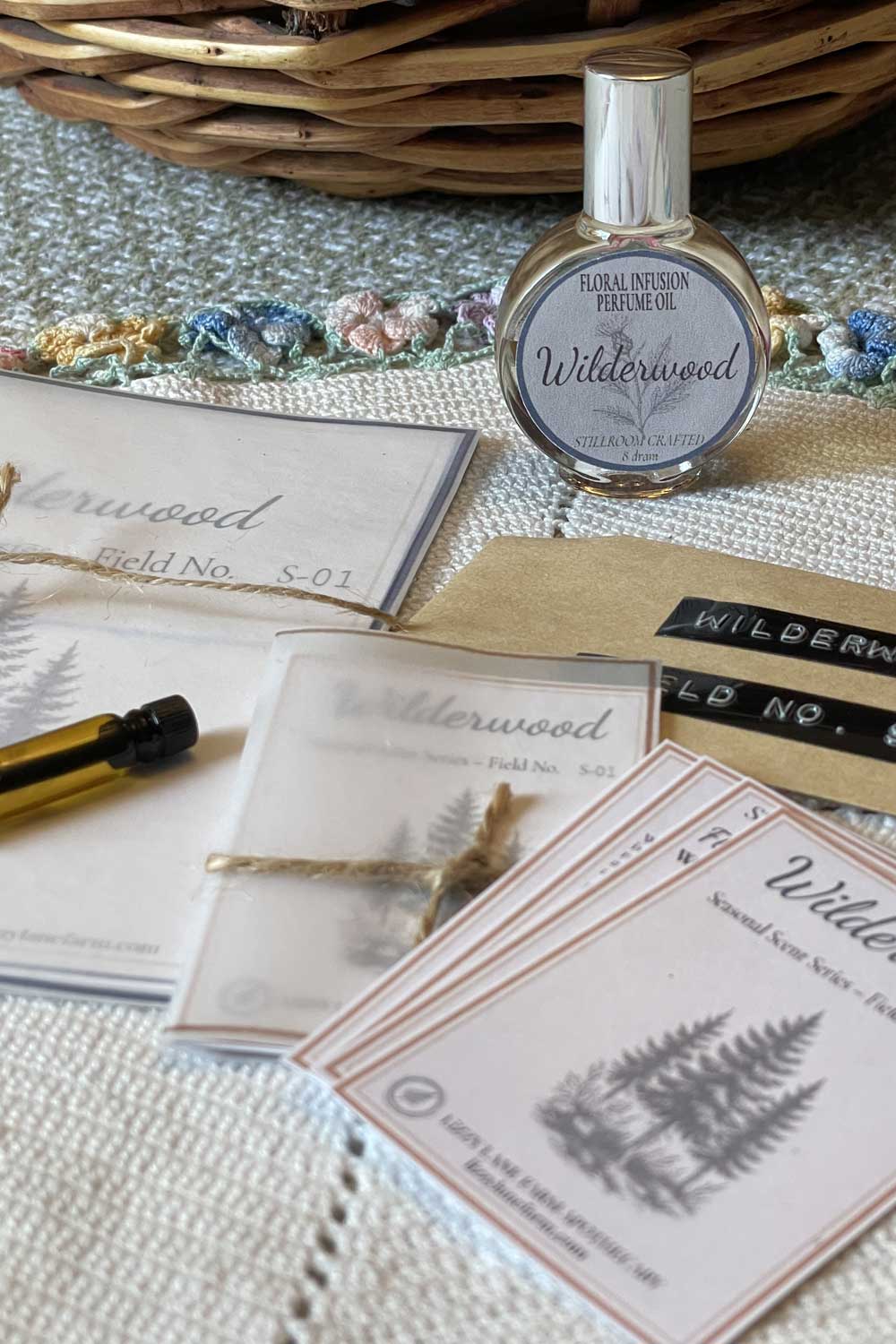 The wildwood perfume part of the seasonal floral infused collection. Both the large and sample sized field guide cards and perfume bottles resting on a vintage linen.