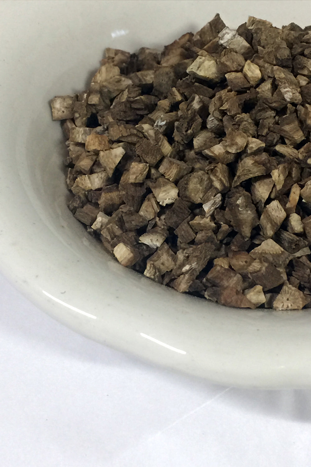 Close-up of cut and dried organic burdock root in a rustic bowl, highlighting the earthy texture and natural hues of the herb.