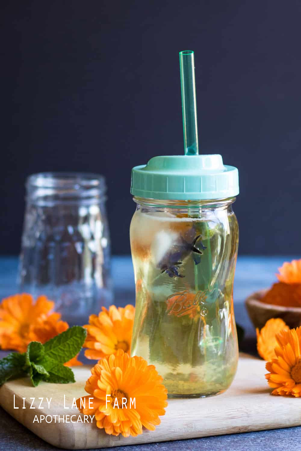 Refreshing iced tea with bright orange Calendula flowers floating on top, served in a glass with a lid and straw, highlighting the cooling, calming qualities of Calendula in a delightful summer drink.