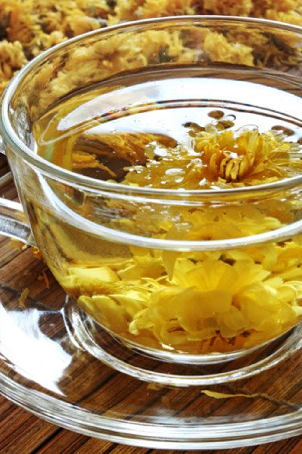 A clear glass bowl filled with golden olive oil, infusing with freshly dried Chrysanthemum petals, capturing the essence of herbal craftsmanship.