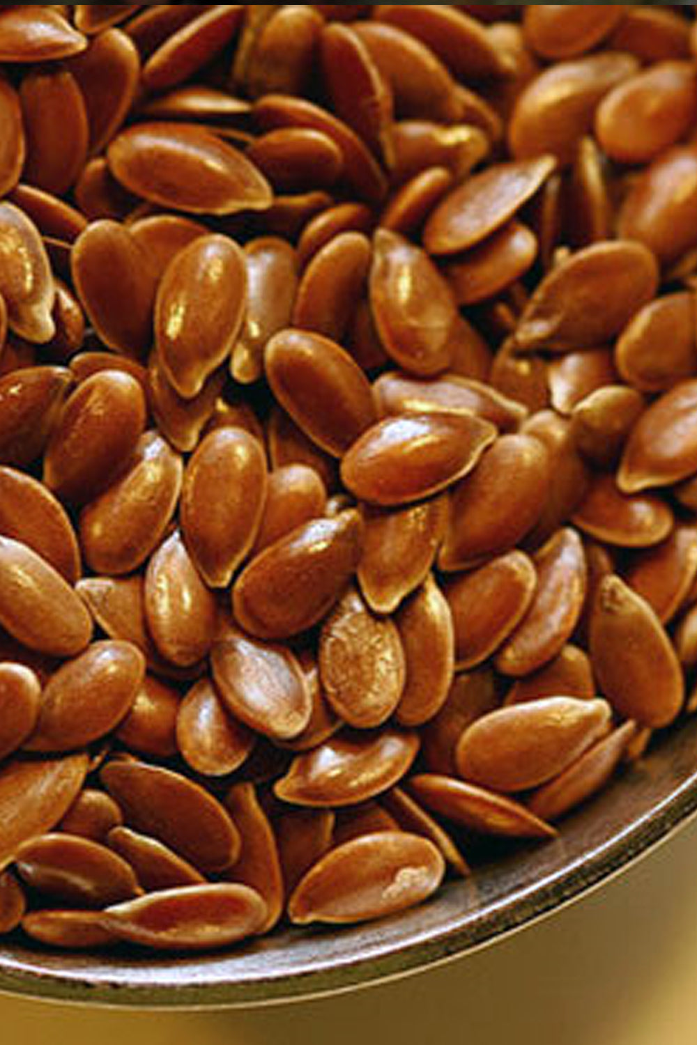 A close-up of freshly dried organic flax seeds in a rustic wooden bowl—rich brown, glossy, and ready for the kitchen.