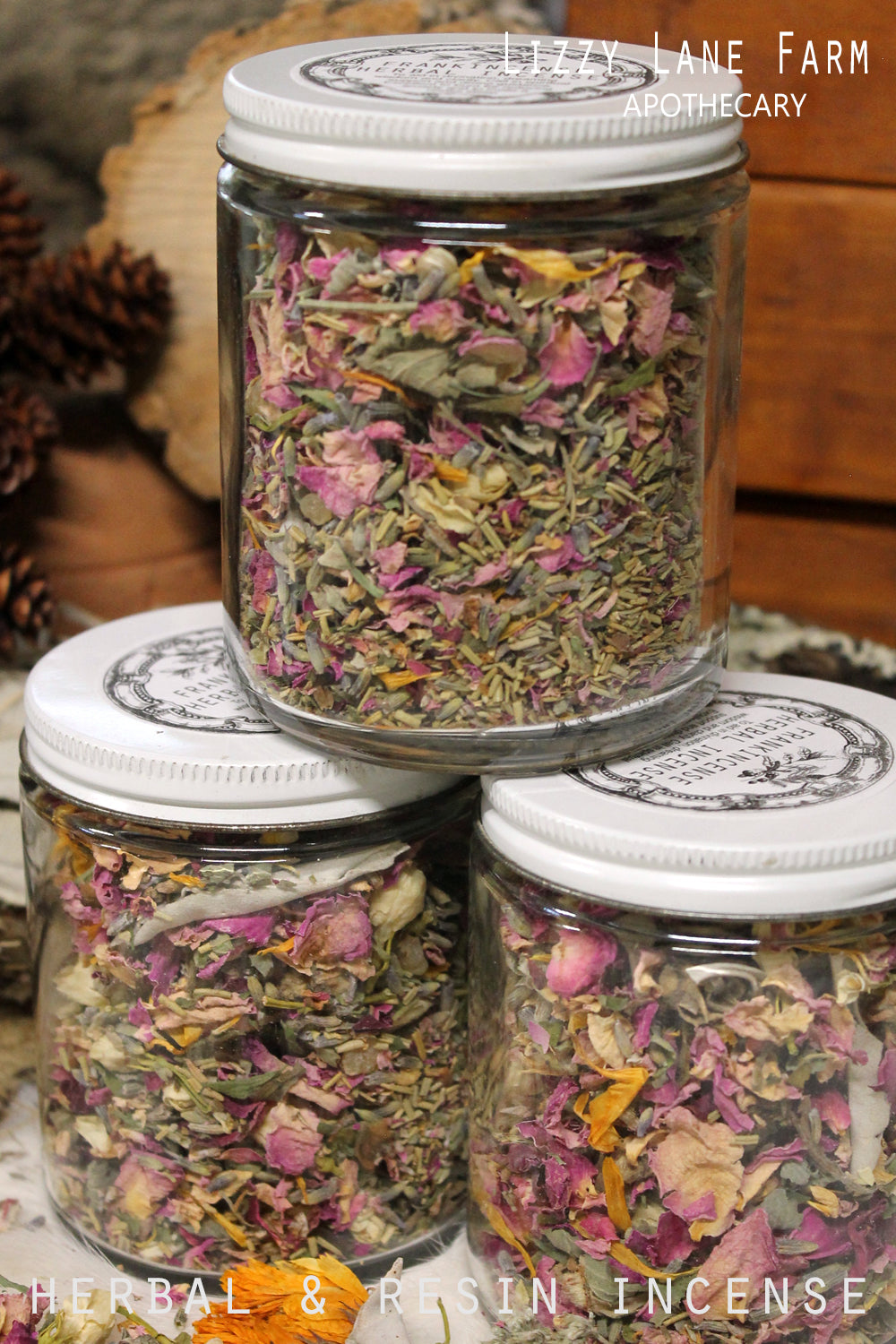Stack of large glass jars with lids, filled with Frolic Herbal Incense, showcasing a vibrant mix of fresh lavender, chamomile, white sage, and resins. A beautifully layered display of natural herbs and botanicals, perfect for home fragrance, relaxation, and slow living.