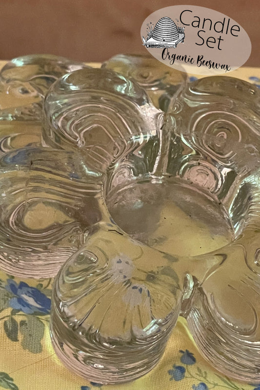 Set of two vintage flower-shaped pressed glass tealight holders shown on a lace-covered table in natural light. Photographed from above and side angles to highlight floral shape and sturdy base.