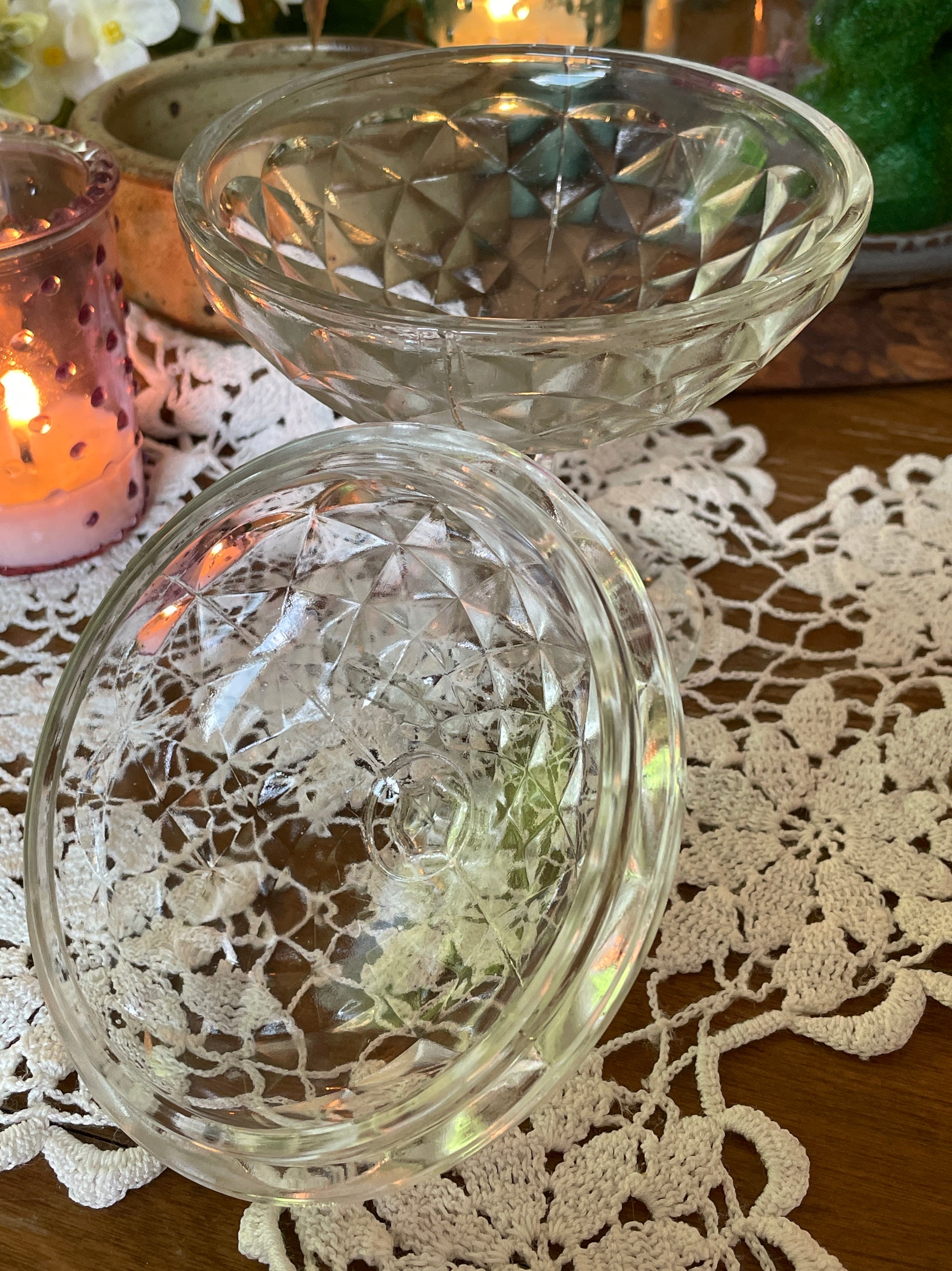 Side angle of antique powder jar showing cut diamond pattern and elegant pedestal base – styled with warm candlelight and vintage doily.