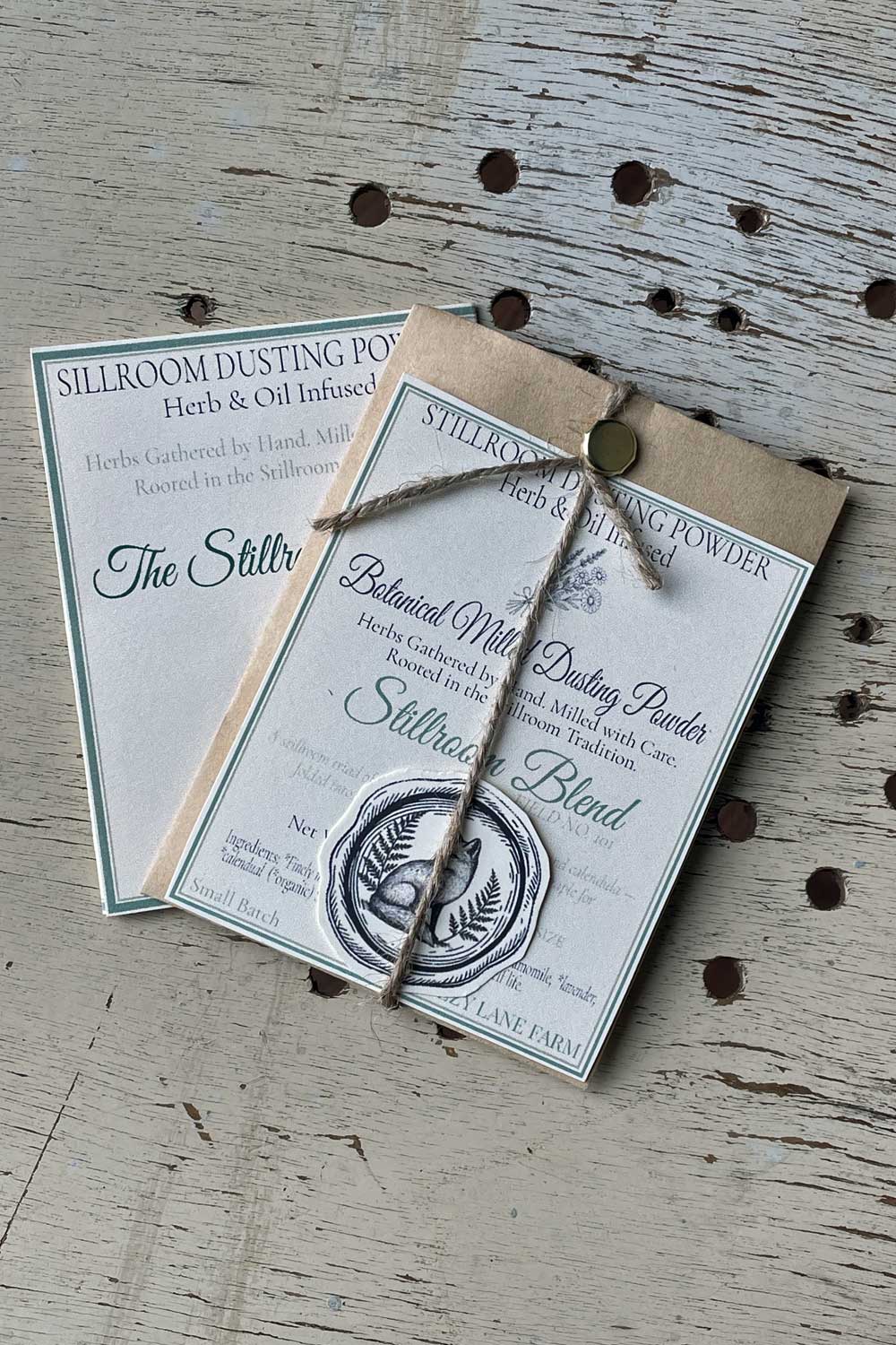 Stillroom Blend Dusting Powder archival cards and coin envelope packaging with apothecary design.