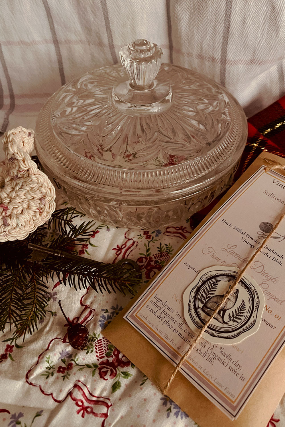 Vintage 1960s Avon Crystalique powder dish with handmade Lavender Dragée Stillroom Dusting Powder set, styled with pine, tartan, and winter linens.