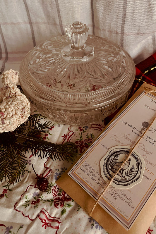 Vintage 1960s Avon Crystalique powder dish with handmade Lavender Dragée Stillroom Dusting Powder set, styled with pine, tartan, and winter linens.