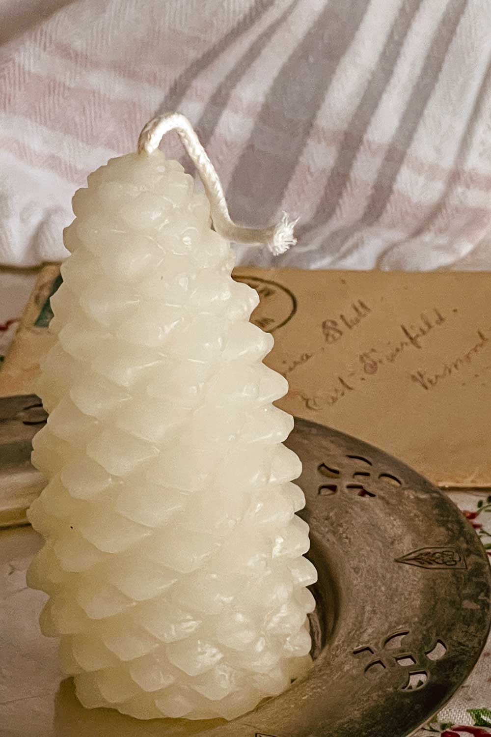 White beeswax pinecone candle displayed on an antique silver dish — a limited Midwinter Archive winter keepsake, perfect for cottagecore gifting.