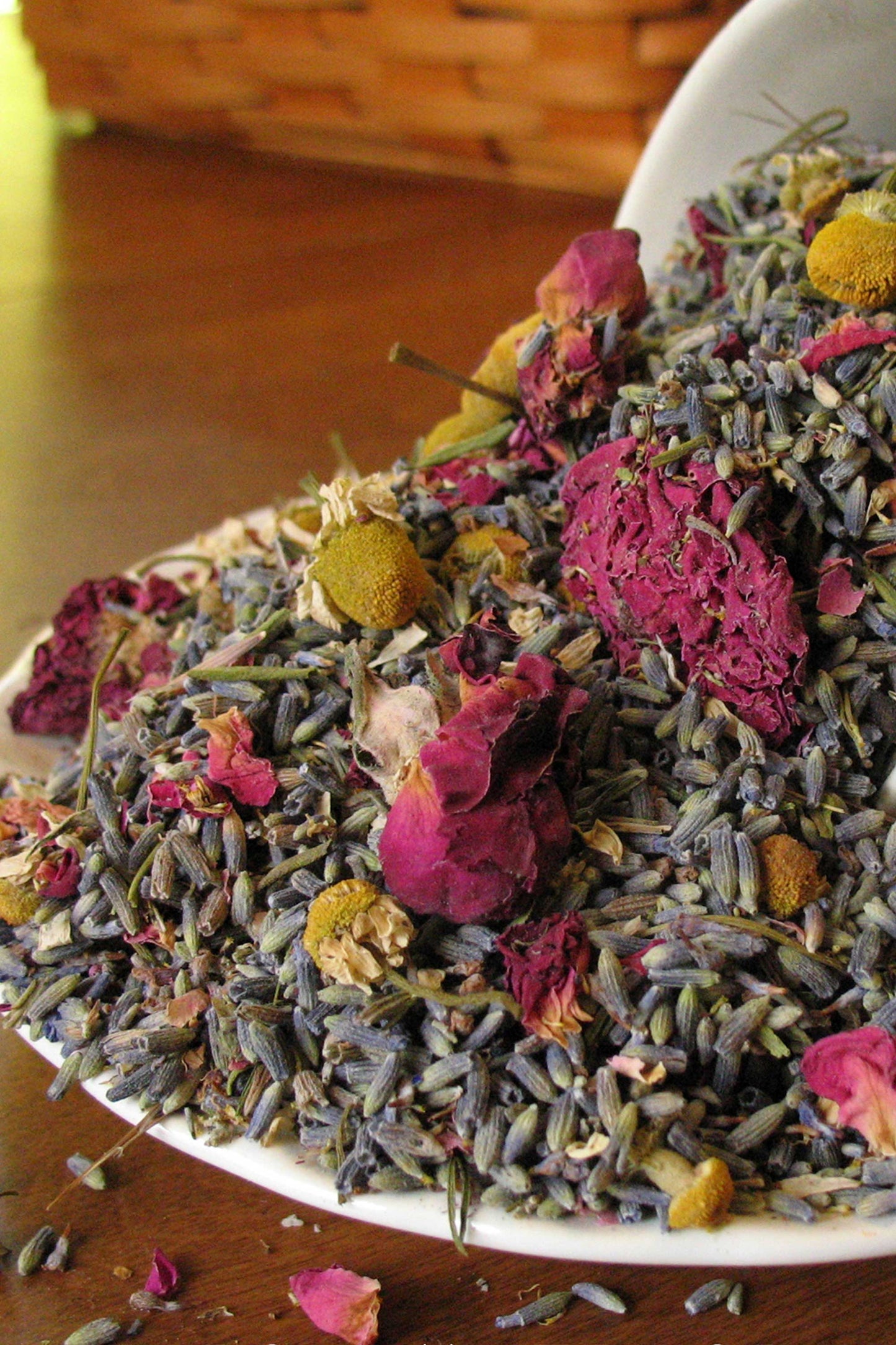 Close-up of Chamomile Summer potpourri with dried lavender buds, rose petals, and chamomile flowers on a white dish.