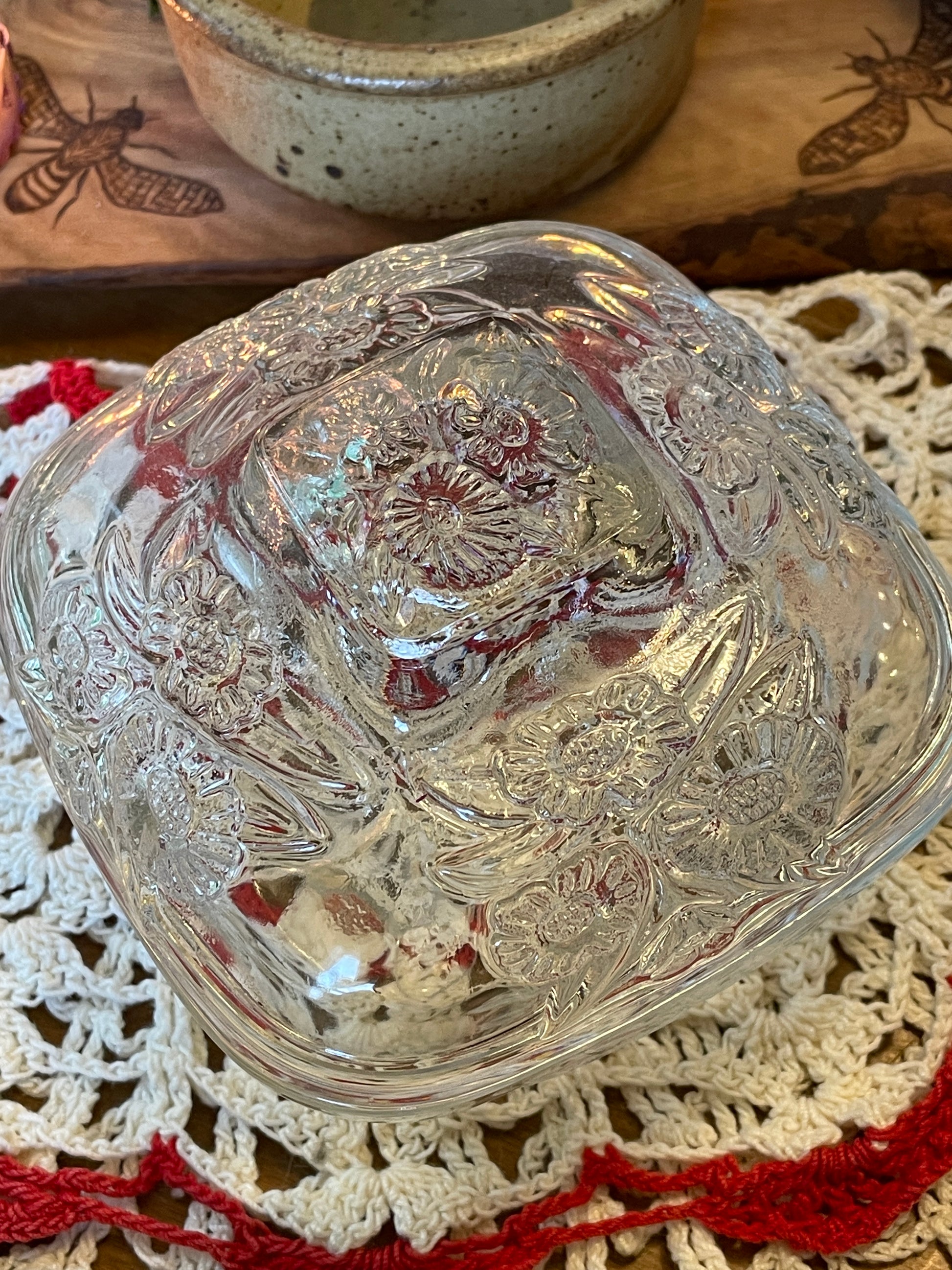 Close-up of vintage body powder dish featuring daisy pattern glasswork and warm candlelight in the background – New England antique vanity decor.