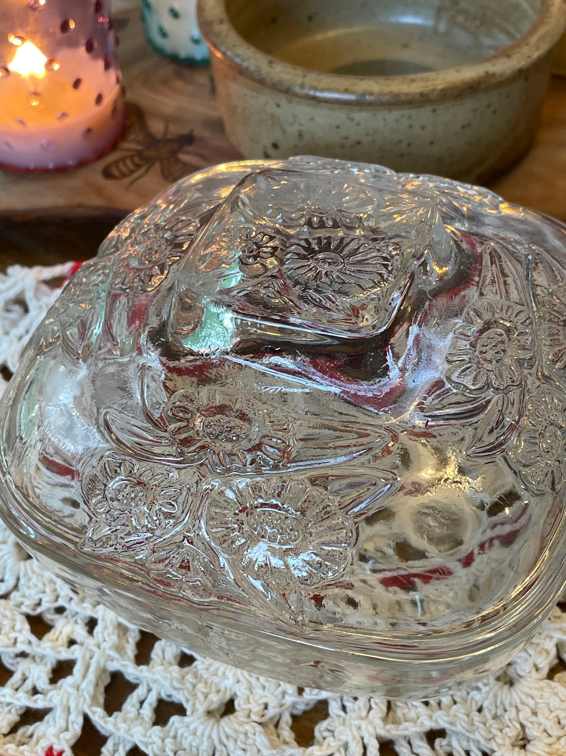 Close-up of vintage body powder dish featuring daisy pattern glasswork and warm candlelight in the background – New England antique vanity decor.