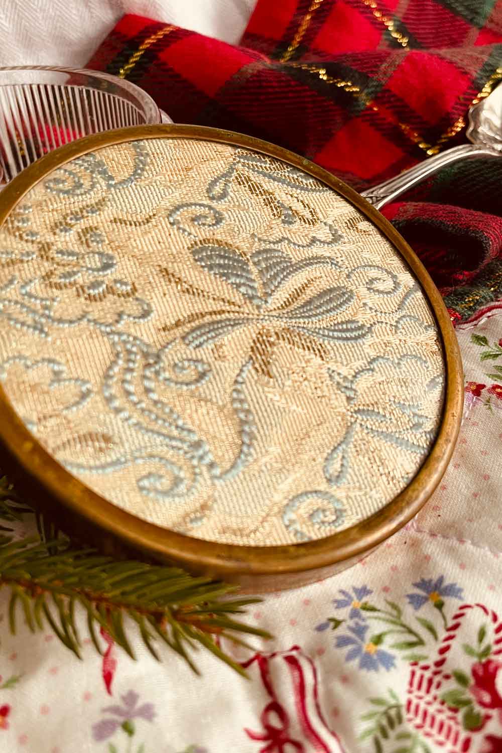 Close-up of gold and pale blue Jacquard fabric lid on vintage glass powder dish, antique vanity style.
