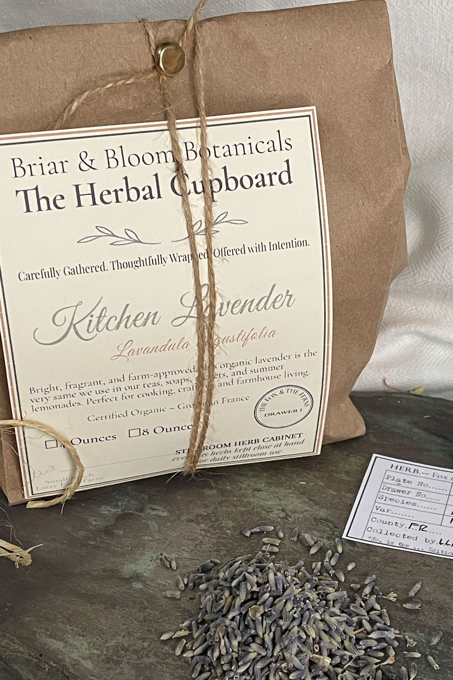 Food-grade lavender buds packaged in a brown paper bag with twine and botanical label from the Stillroom Herb Cabinet at Lizzy Lane Farm