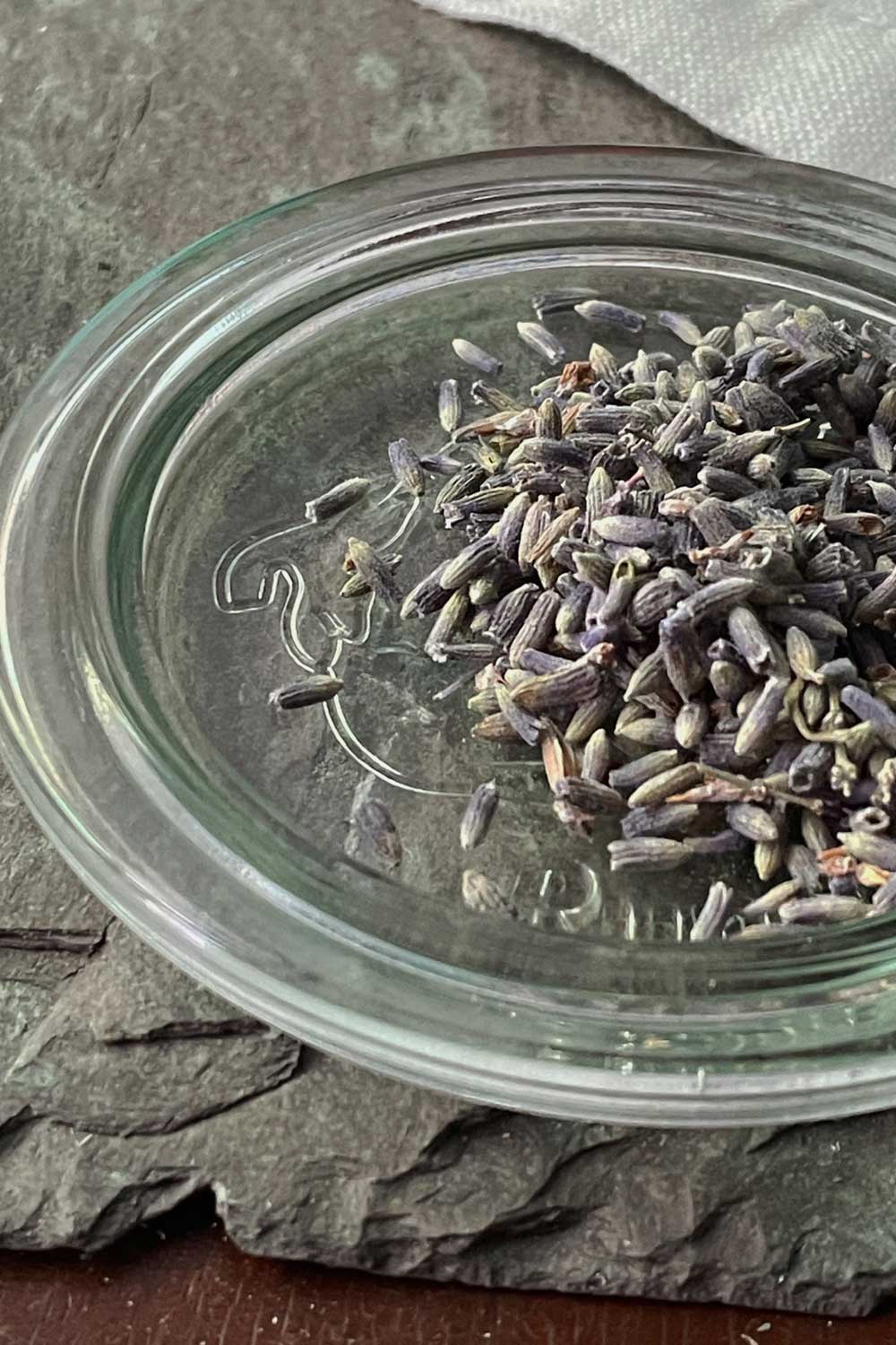 lavender flower loose tea resting on glass canning jar lid. part of the rest and ritual herbal tea collection
