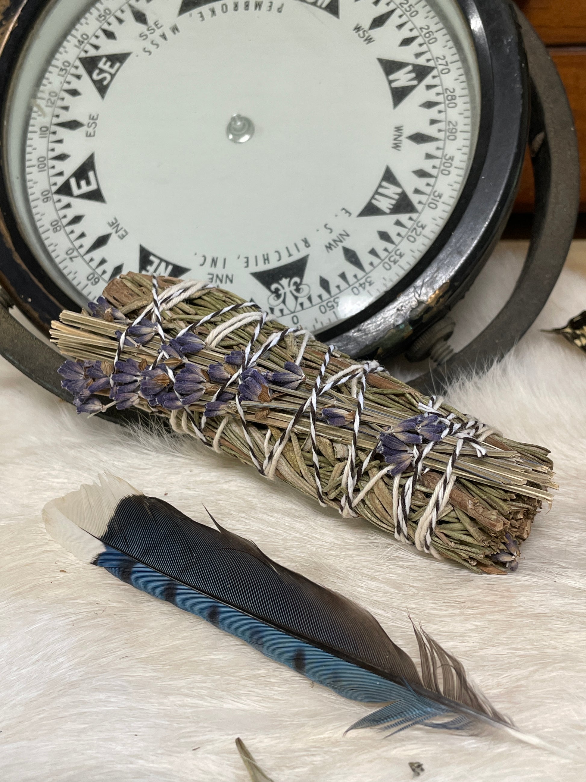 a farm grown lavender and rosemary herb budle hand tied resting on a rabbit fur and a bird feather close by, part of the little comforts from lizzy lane farm