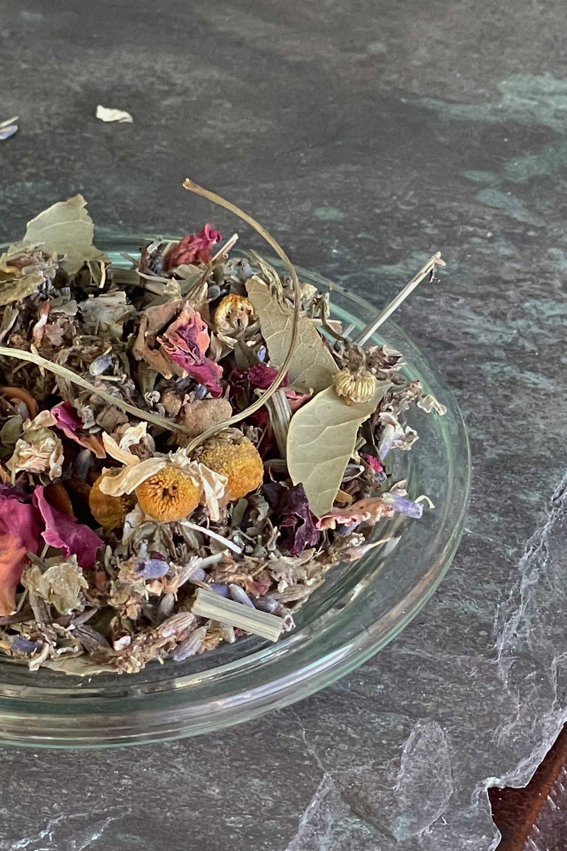 Loose Night Garden herbal blend in a glass bowl featuring lavender, rose petals, chamomile, mugwort and star anise on a dark farmhouse surface