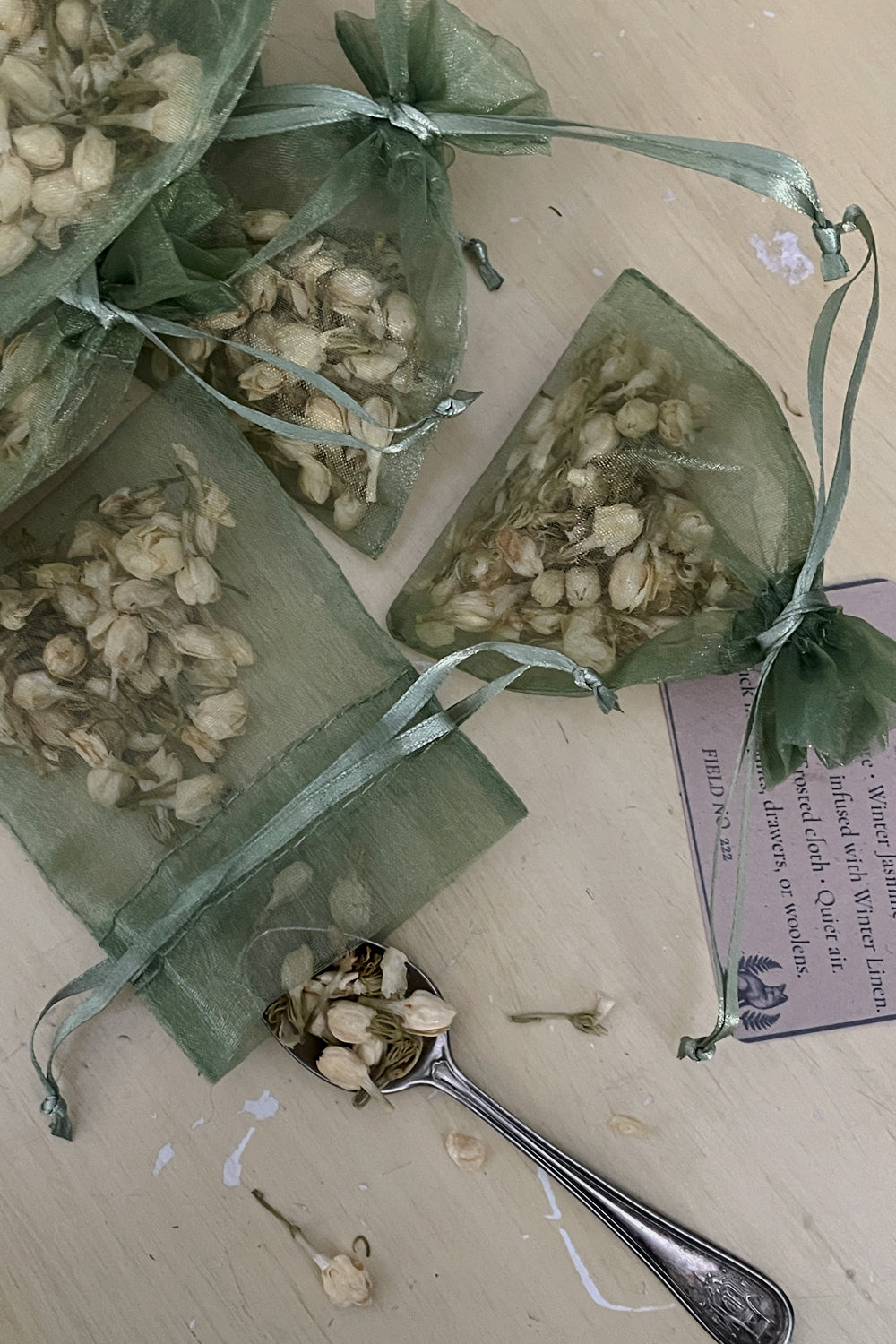 Hand-filled Jasmine sachets with archive tags and winter greenery — small handmade gifts from the Stillroom winter collection.