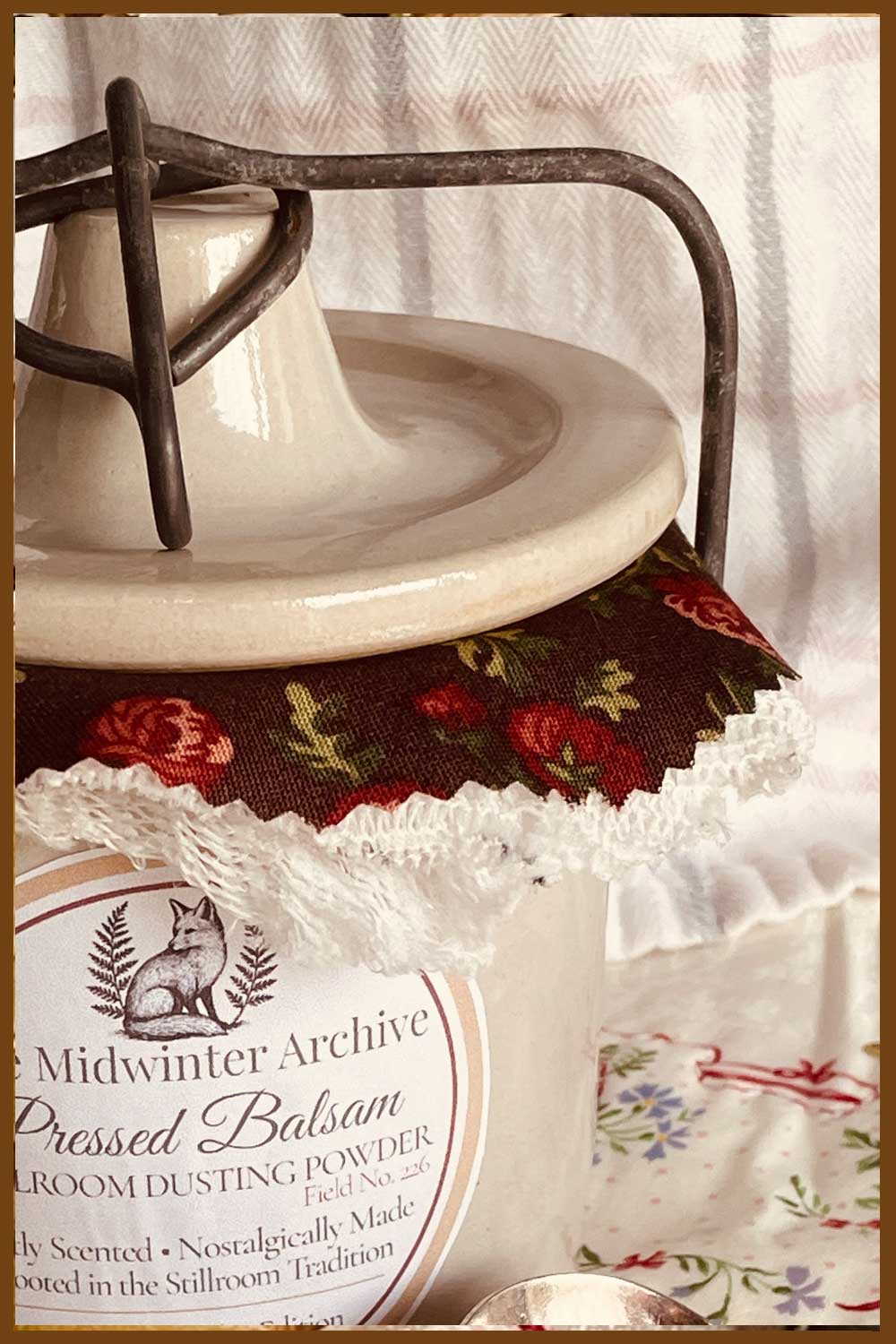 A white vintage Midwinter Powder Crock with lace and floral calico covering — filled with balsam dusting powder for the Stillroom Christmas collection.