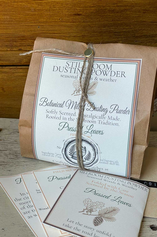 Pressed Leaves Dusting Powder in bulk 12 oz, with Archival Series Cards sitting on rustic chair.