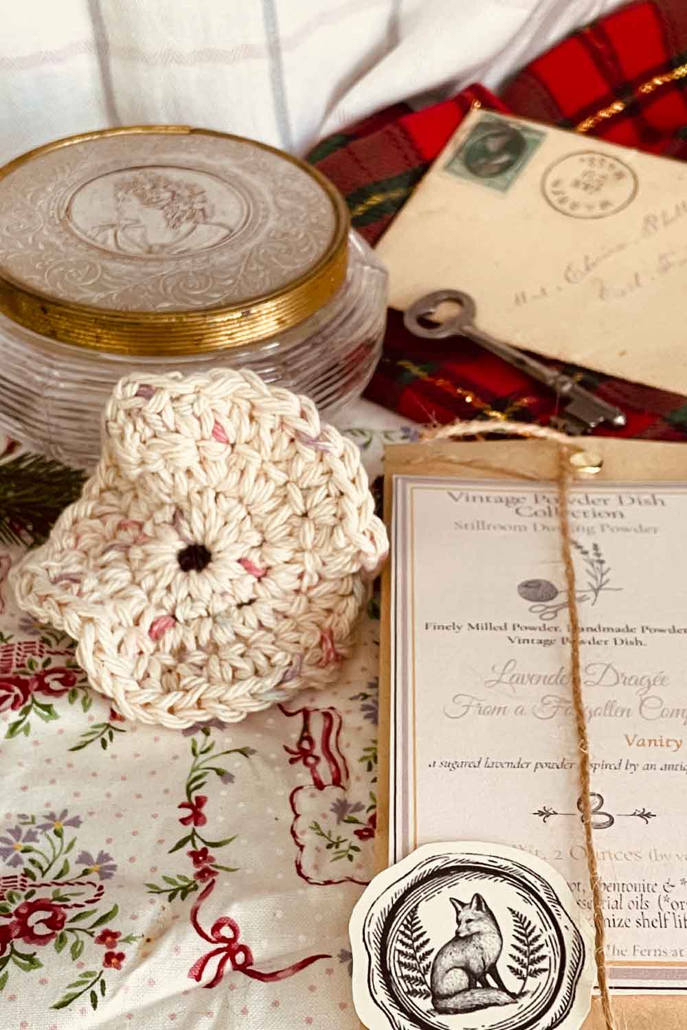 Vintage cameo powder dish shown beside a handmade powder puff and Stillroom Archive cards, styled with tartan ribbon and holiday accents.