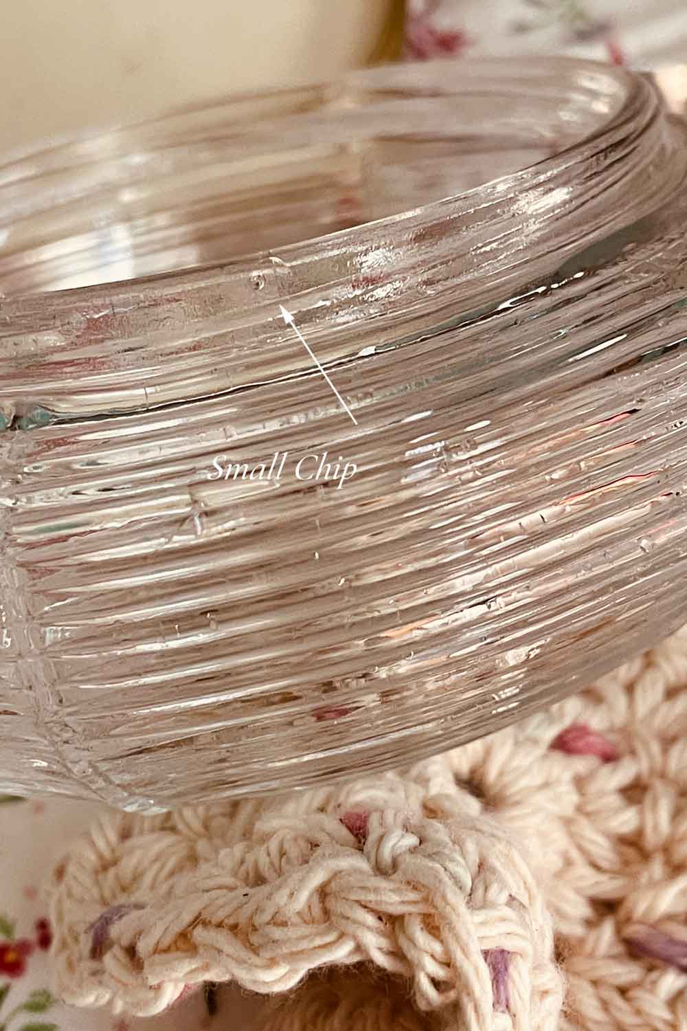 Close-up of the vintage powder dish’s glass rim showing a tiny flea-bite chip, clearly marked for buyer reference.