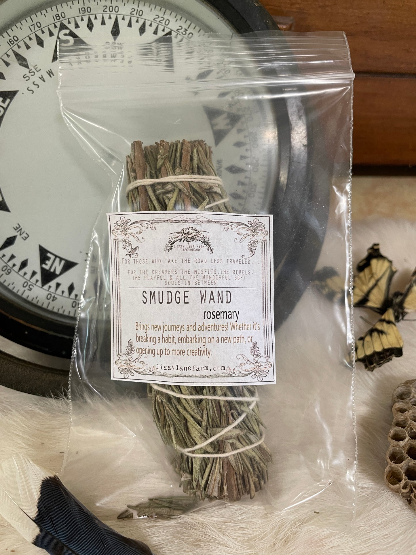 A small hand-tied rosemary smudge bundle resting on fur with soft lighting and vintage garden trimmings. The herbal texture and green tones are visible and calming.