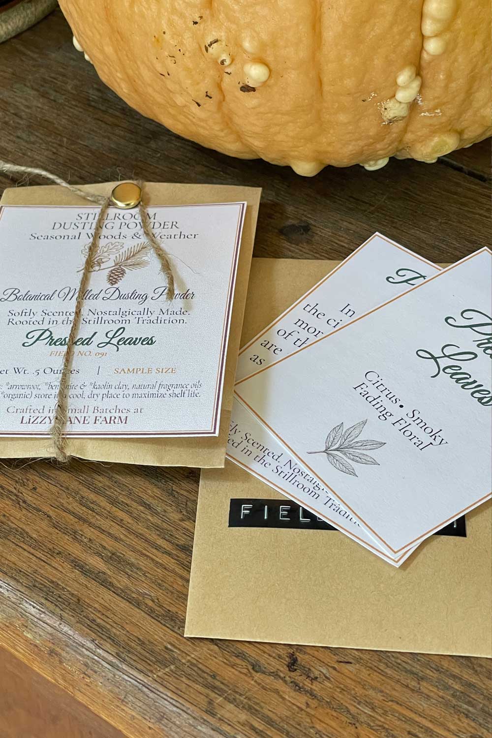 pressed leaves scented botanical dusting powder, part of the seasonal woods & Weather fall collection. sample sized envelope and archival cards, peeking out the archive envelope marked with a rustic dymo label with field no.