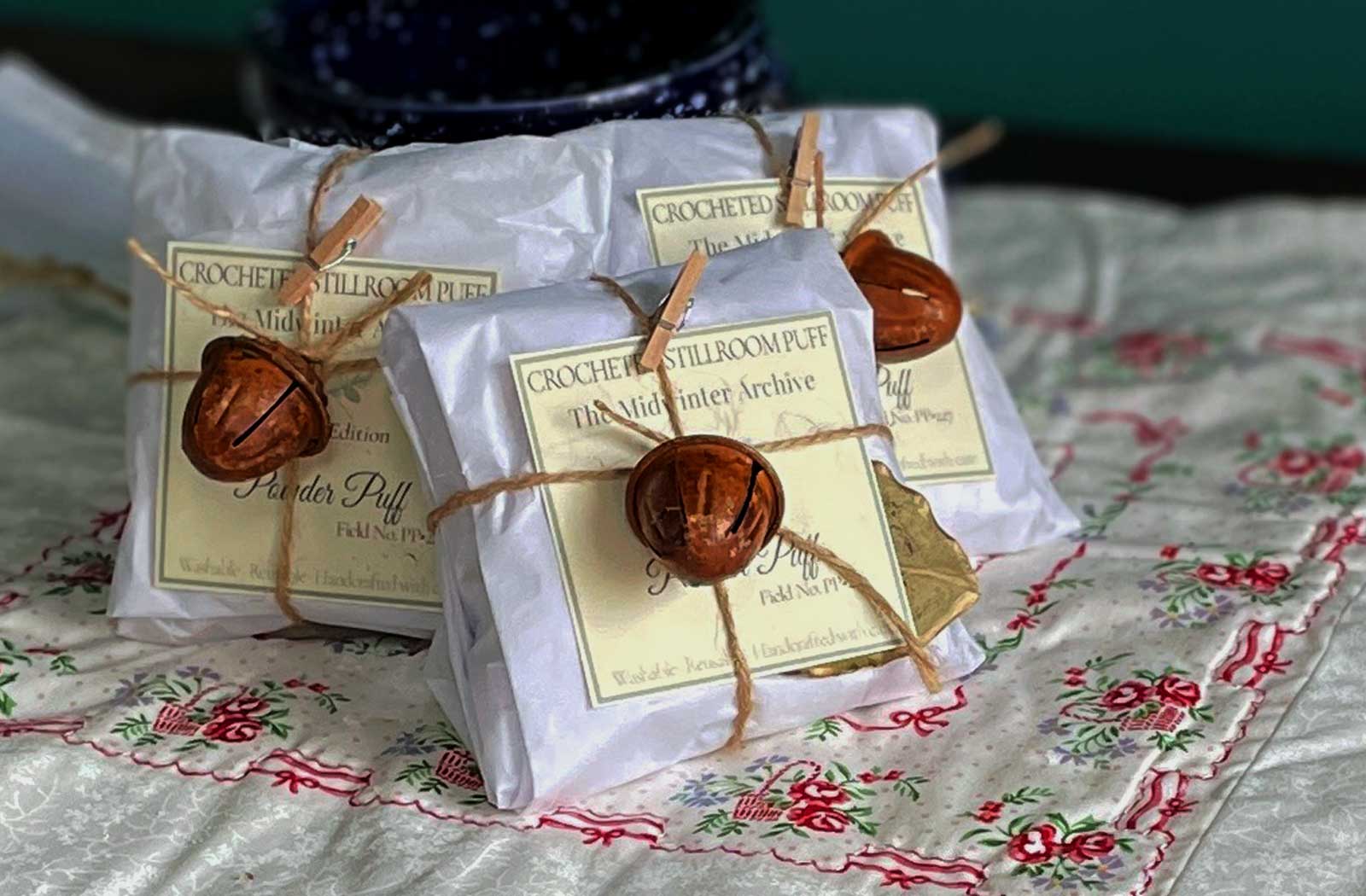 Handcrafted Midwinter Archive dusting powder puffs wrapped in cloth and twine with copper bells — limited edition holiday stillroom collection by Lizzy Lane Farm.