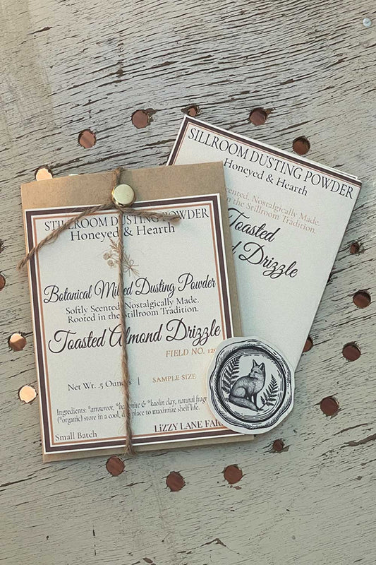 Toasted Almond Drizzle Dusting Powder, 12 oz bulk edition with Stillroom Archive fragment cards — vintage farmhouse holiday scent with goldenrod icon.