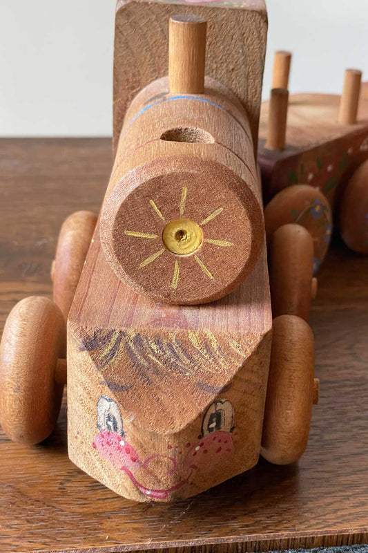 Wooden toy train with a face on a wooden surface