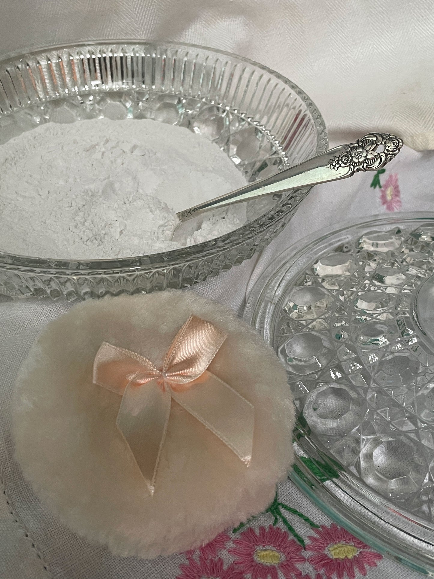 Interior view of vintage glass powder dish with lavender powder settled inside and spoon resting within the bowl.