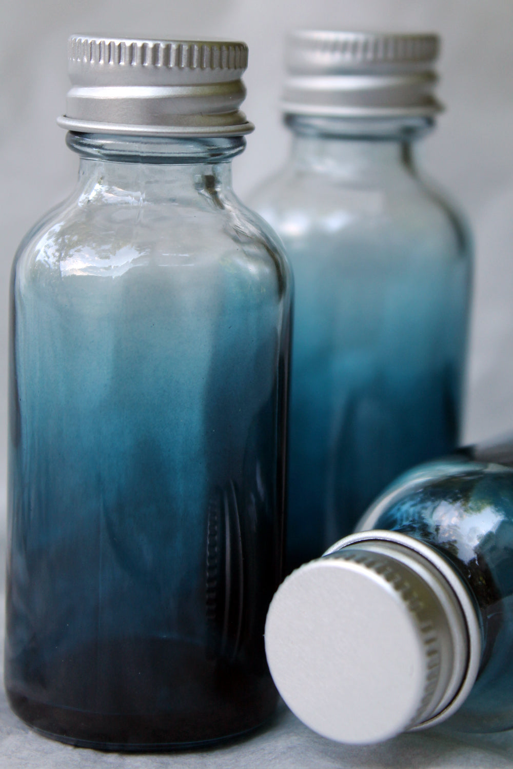 blue shaded boston round bottles with silver twist cap