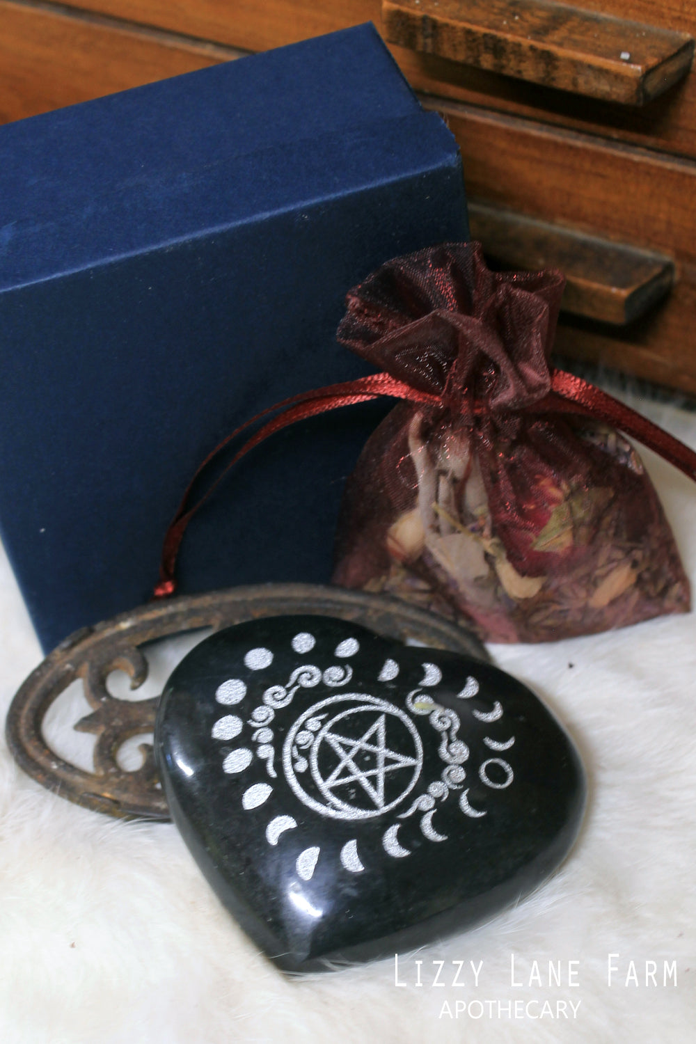 A beautifully polished Black Tourmaline stone heart with silver moon phases circling a pentacle.