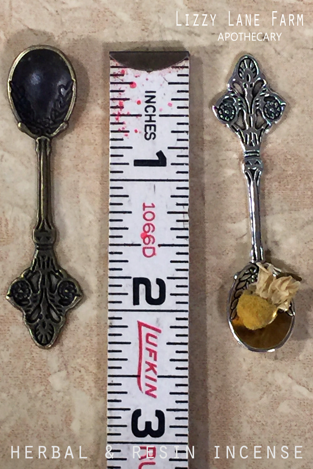 A close-up of two metal herbal spoons (silver tone and brass), with a ruler placed beside them to show their size of approximately 2.25" long. These small spoons are perfect for measuring and sprinkling loose incense or herbal blends, making them an ideal addition to your incense accessory kit.